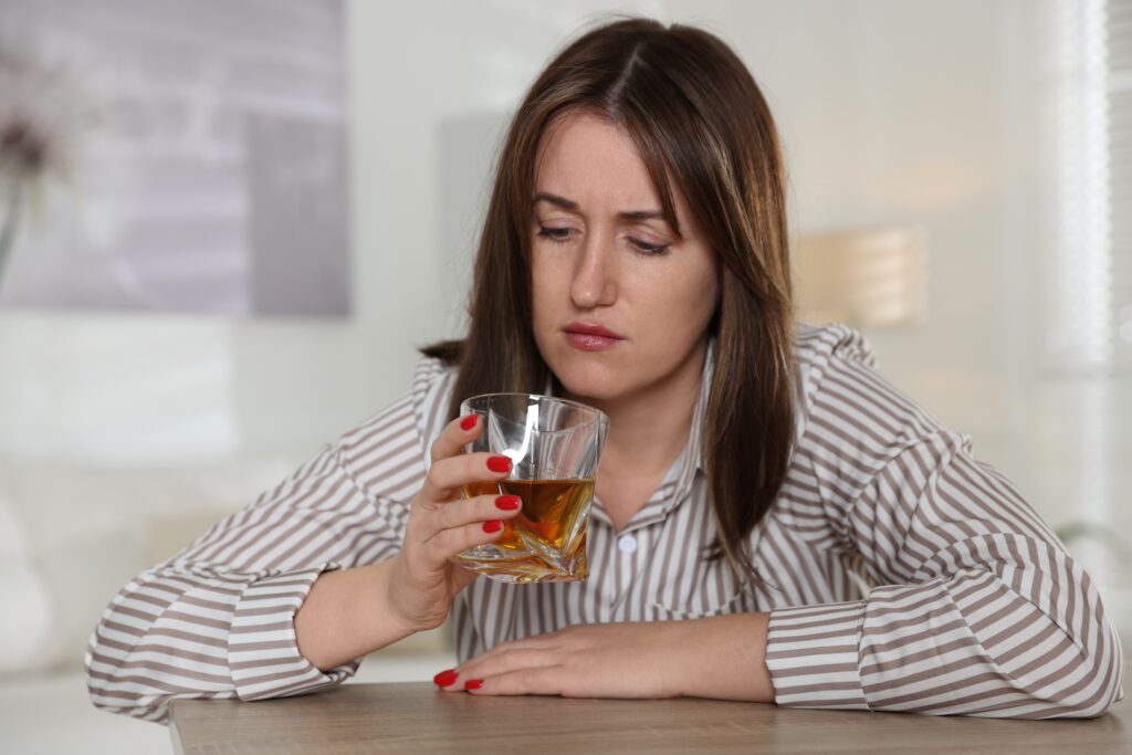 Woman struggling with alcohol addiction drinking alone